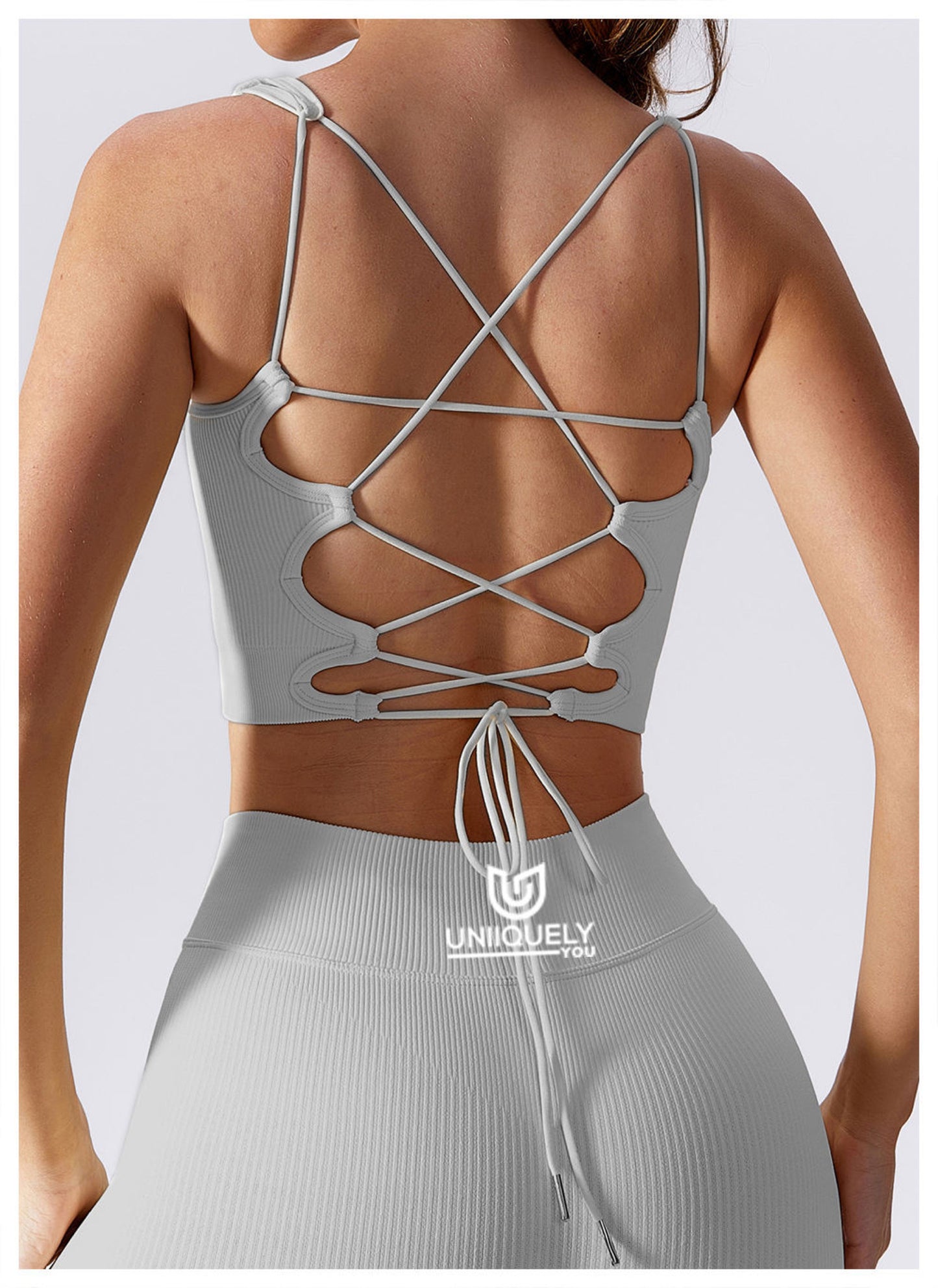 Grey rippled cross-back sports bra with seamless design, supportive fit, breathable fabric, and stylish strappy back detail for workouts and activewear
