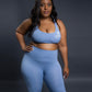Light blue seamless workout set with cross-back sports bra and high-waisted leggings featuring butt lift design, waist-slimming fit, and smooth sculpting fabric
