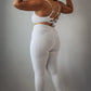 Women’s grey rippled workout set with crossover high-waist leggings that slim the waist and enhance curves, paired with an adjustable cross-strap back sports bra for a sculpted, supportive, and flattering athletic look.