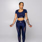 Women’s navy blue suspender workout set with short sleeve crop top, high-waisted leggings with sheer mesh side panels, fitted athletic outfit