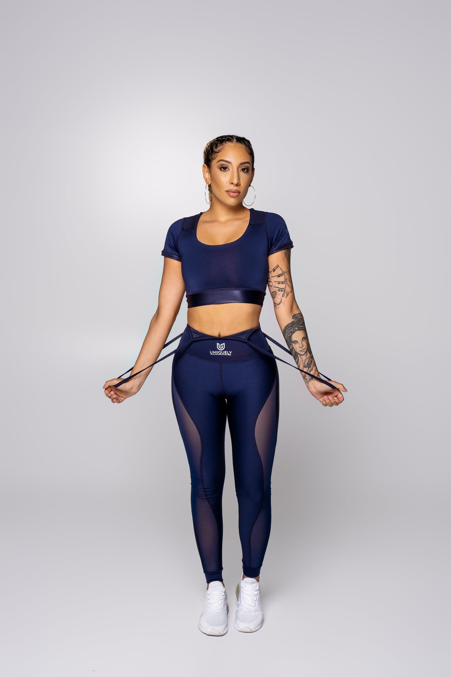Women’s navy blue suspender workout set with short sleeve crop top, high-waisted leggings with sheer mesh side panels, fitted athletic outfit