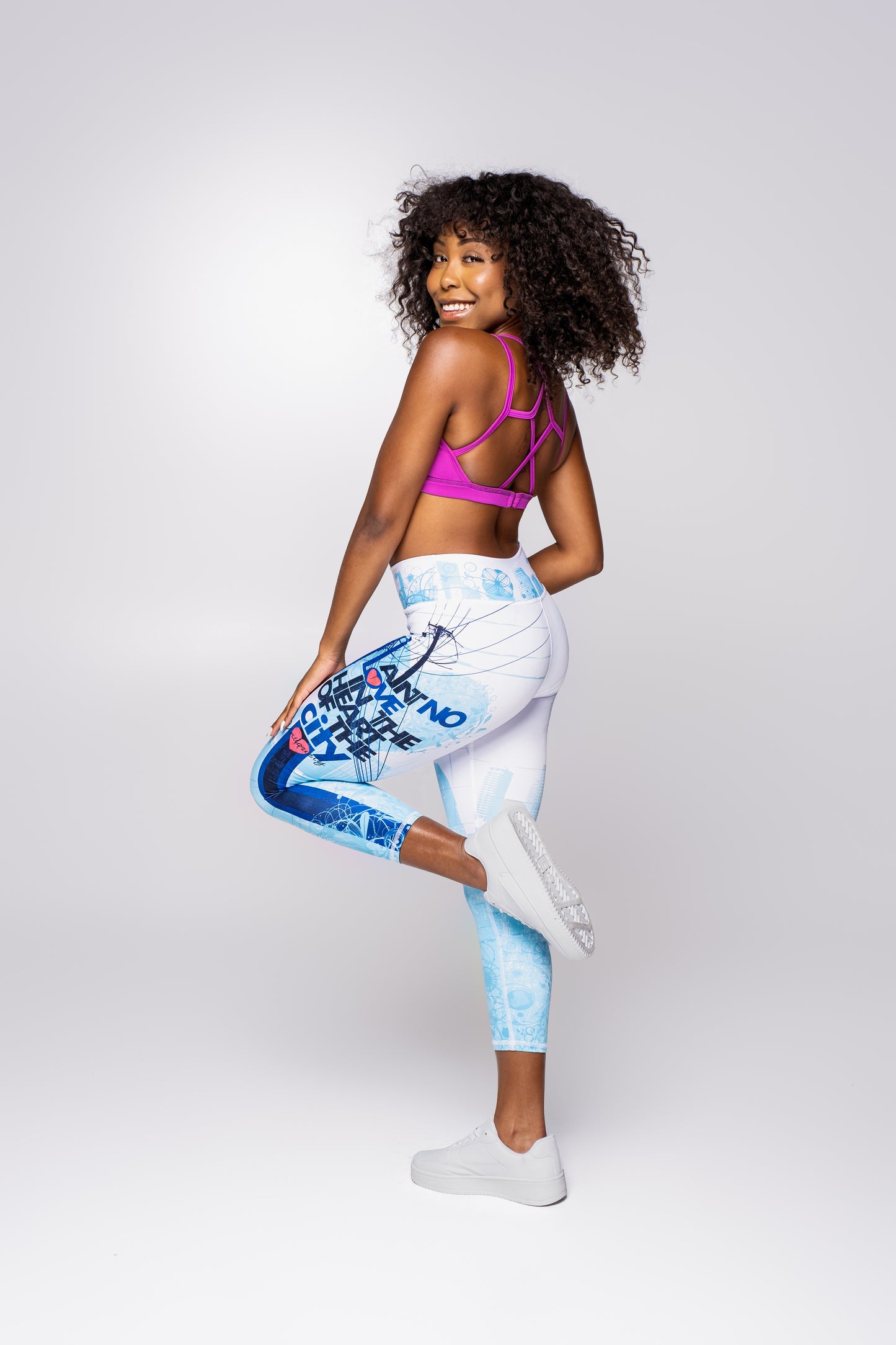 Women’s blue and white graphic print regular-waisted leggings with bold text design, fitted athletic leggings paired with pink strappy sports bra